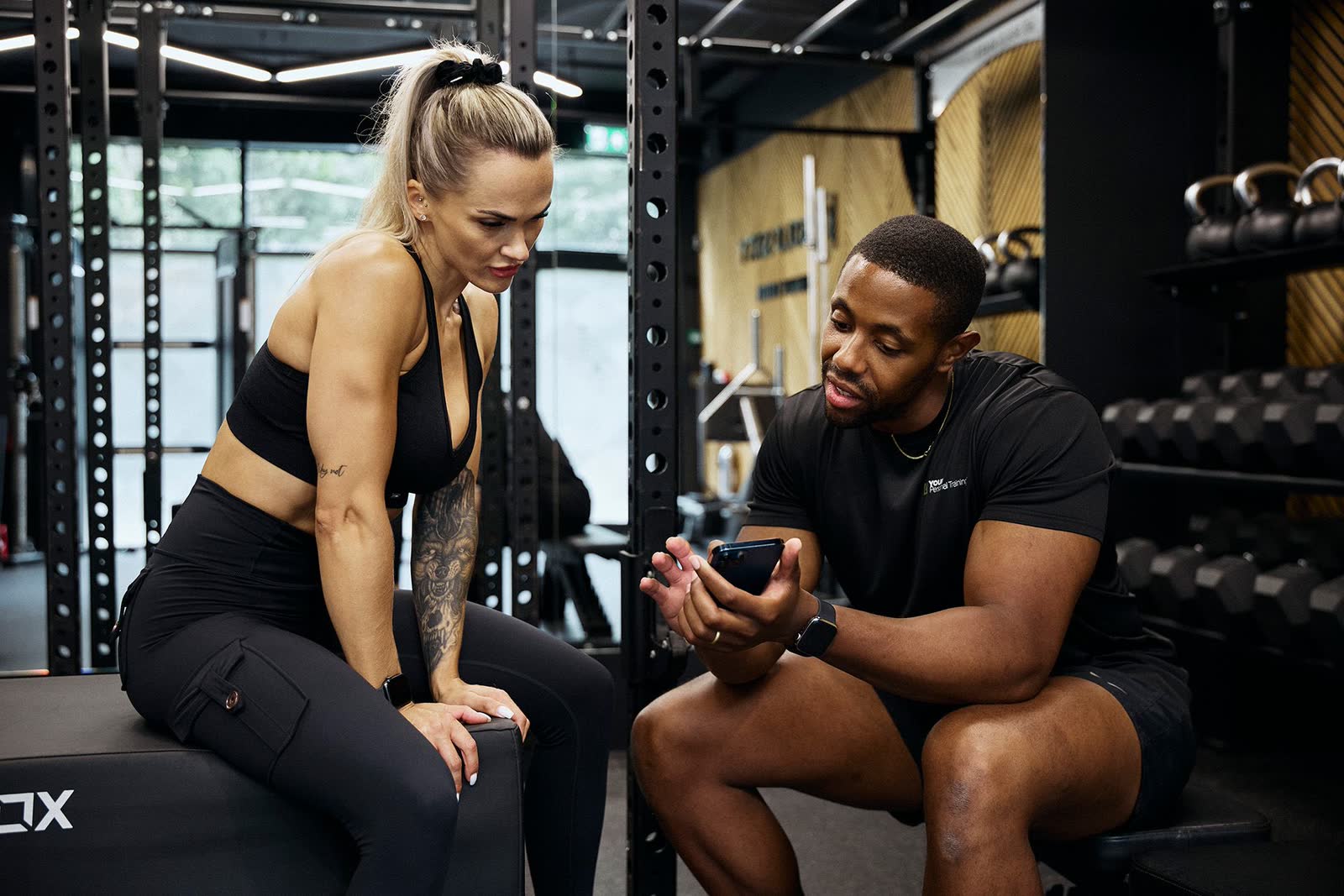 A personal trainer and their client reviewing training data together on a phone